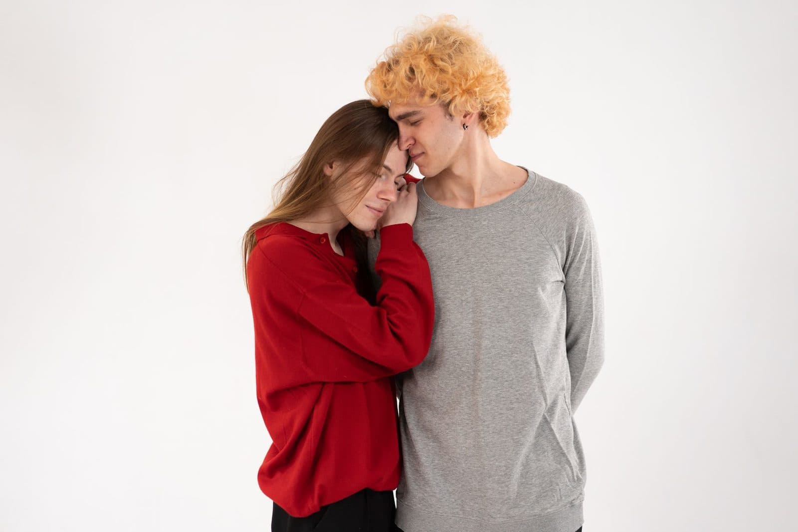 A young couple shares a tender moment in a minimalistic studio environment.