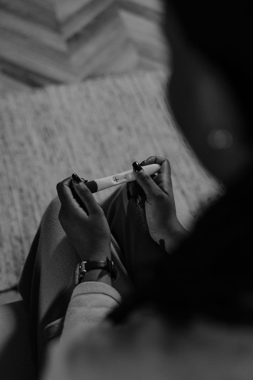 Monochrome image of a woman holding a pregnancy test, capturing anticipation.
