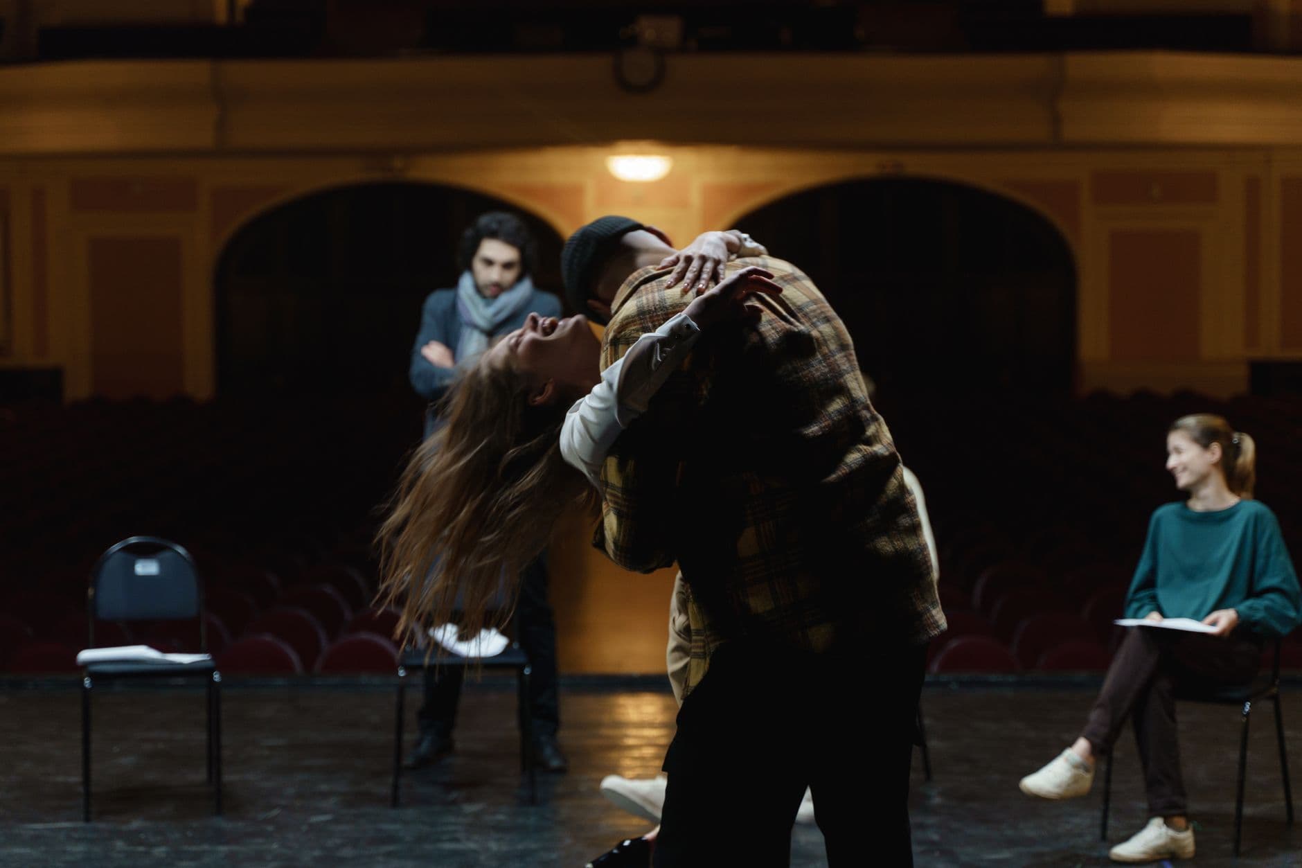 Actors in a dramatic rehearsal on a theater stage, showcasing emotion and performance.