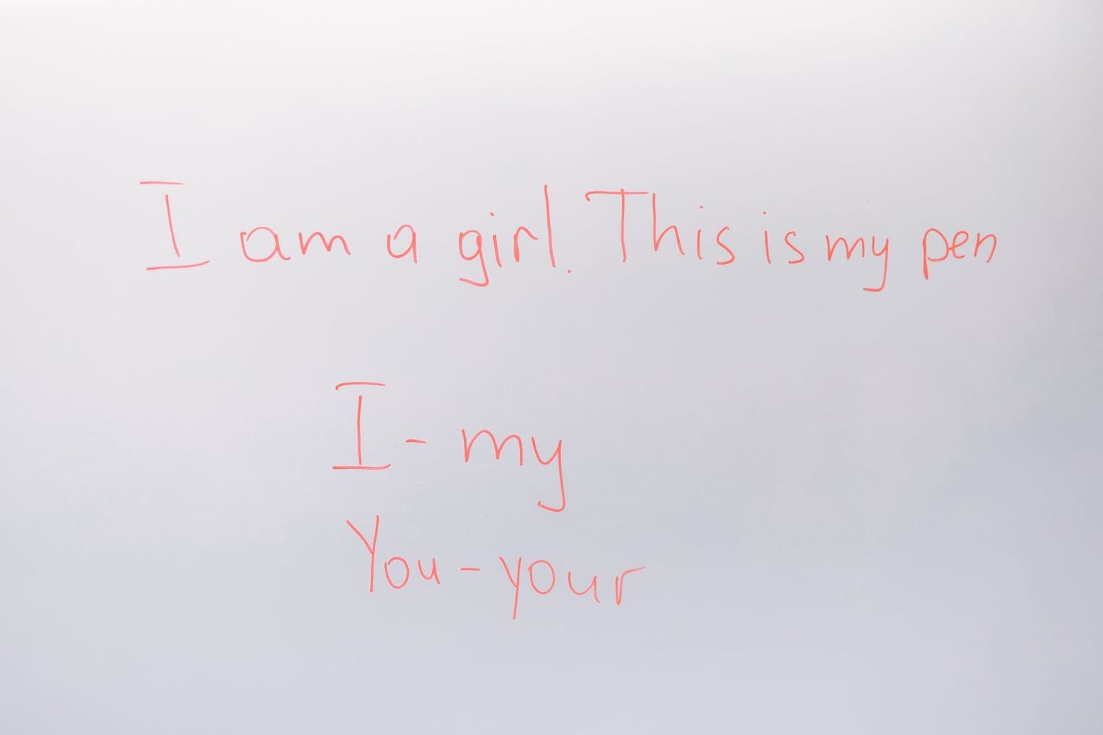 Handwritten English lesson on whiteboard with sentences and pronouns.