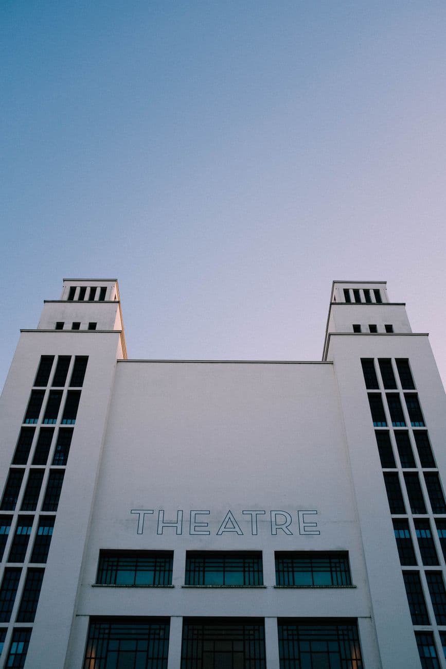 Low angle view of a modern theatre building facade with a clear sky backdrop.
