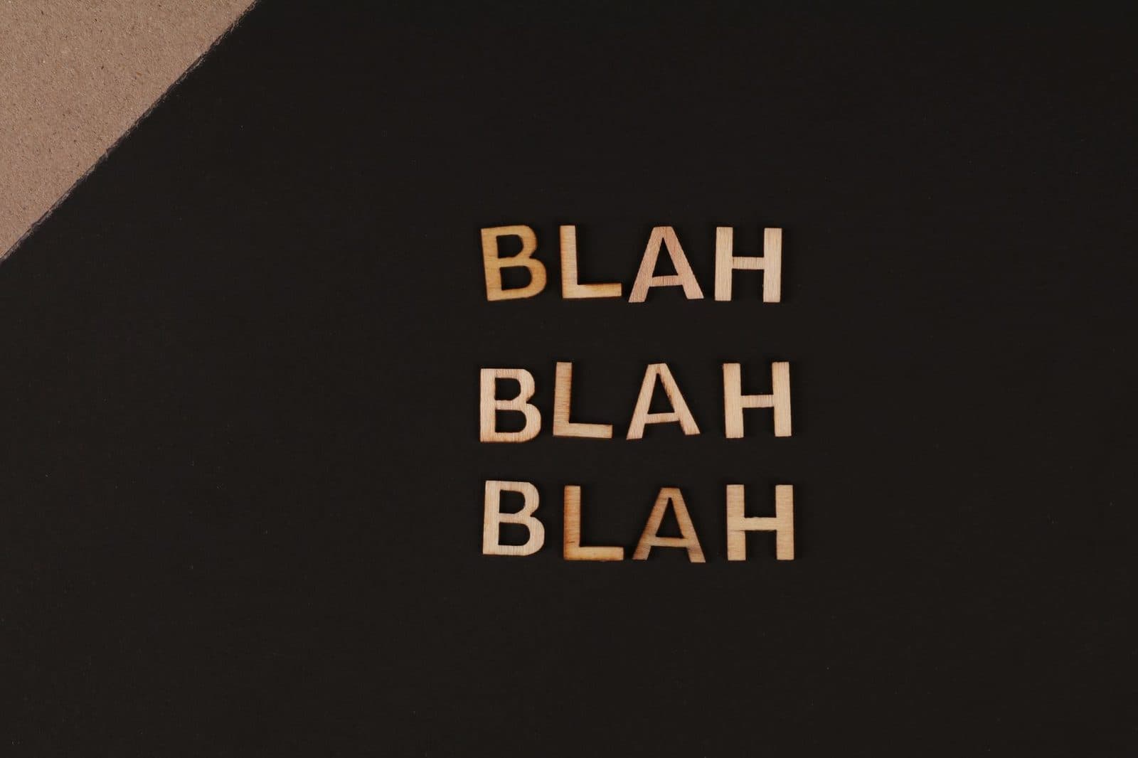 Close-up of wooden letters spelling 'blah', arranged on a black background, offering a conceptual design with copy space.