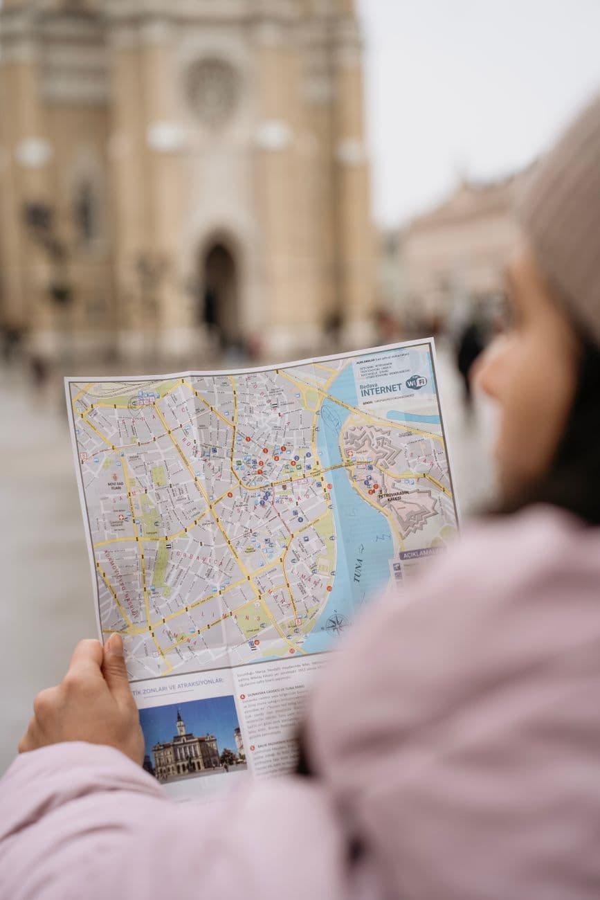 A person holding a city map in front of a cathedral in Novi Sad, Serbia.