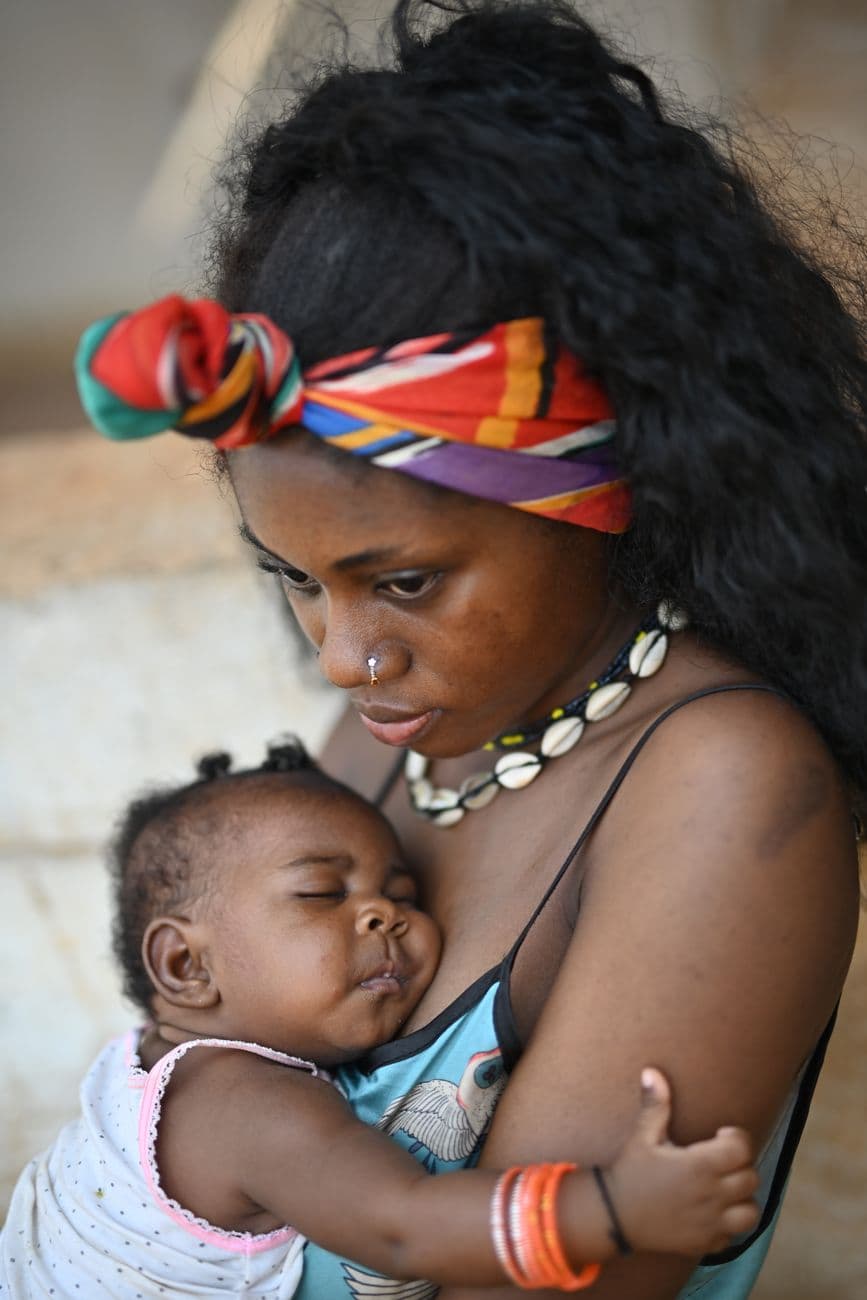 A mother lovingly holds her sleeping baby, showcasing a tender bond in Yaoundé, Cameroon.