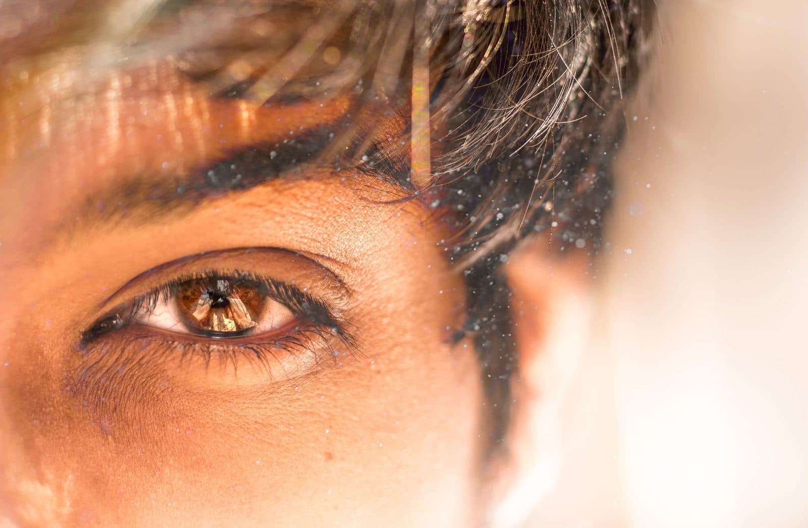 A detailed close-up of a human eye with dust particles reflecting natural light.