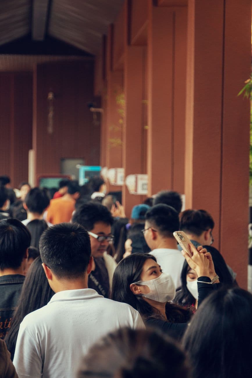 A crowded indoor station with diverse individuals using smartphones, creating a modern travel scene.