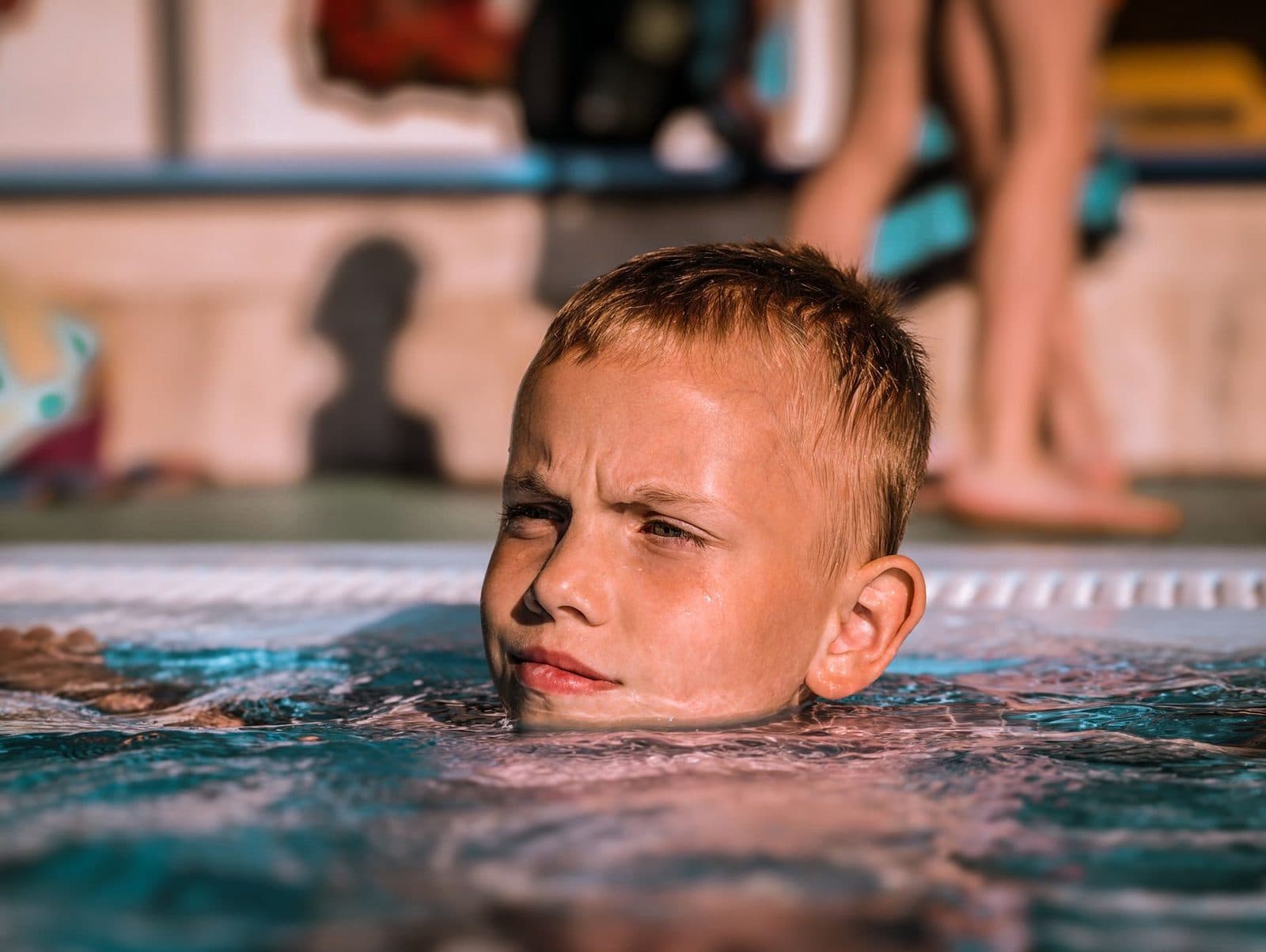 A young boy enjoying a swim in a sunlit outdoor pool. Perfect for summer vacation themes.