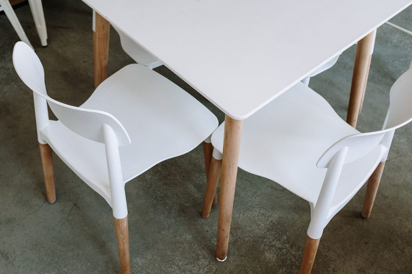 Top view of a modern, minimalist white table and chairs in a cafe setting.