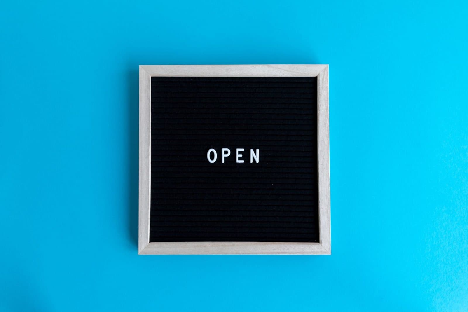 A black signboard with 'OPEN' text on a vibrant blue background.