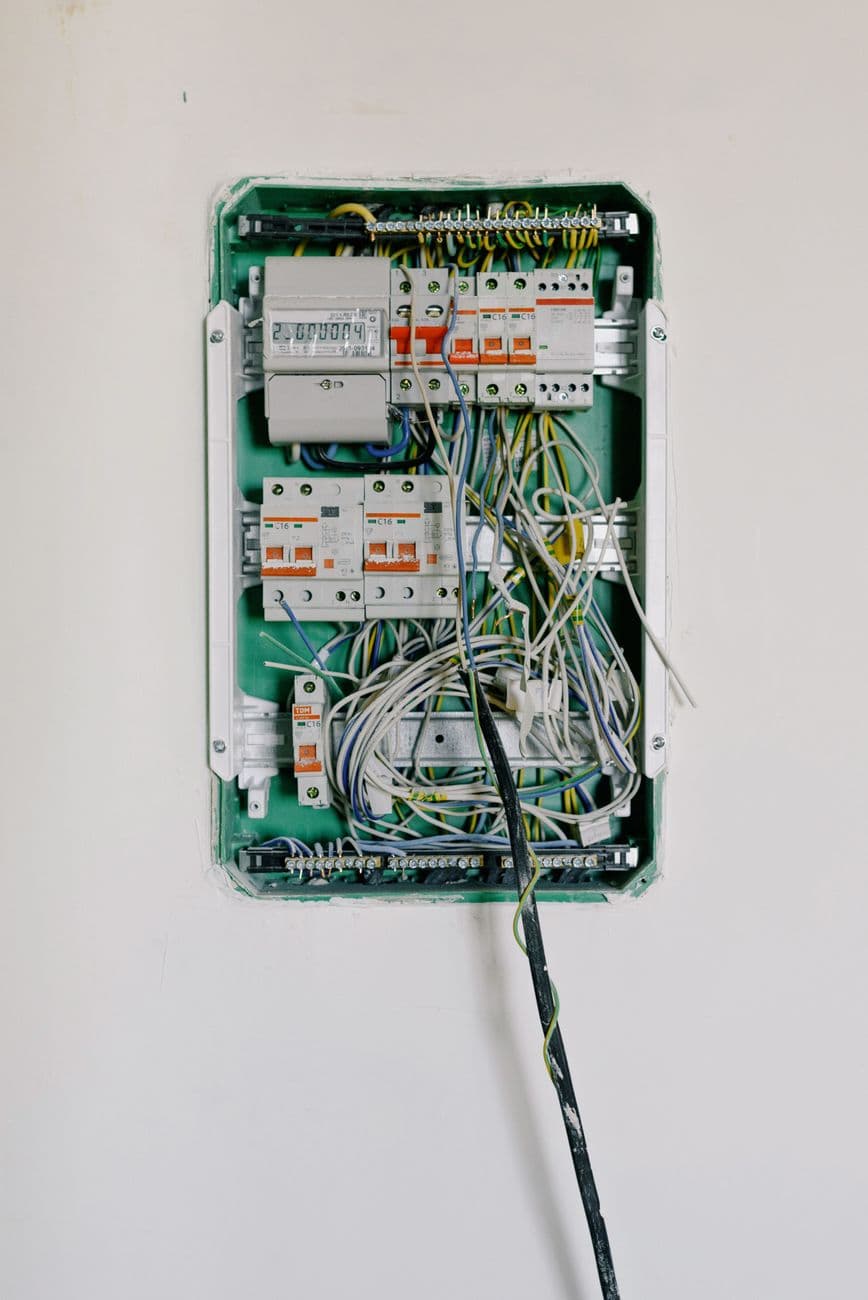 Switchboard with wires connected to electrical switches with circuit breakers installed on white wall