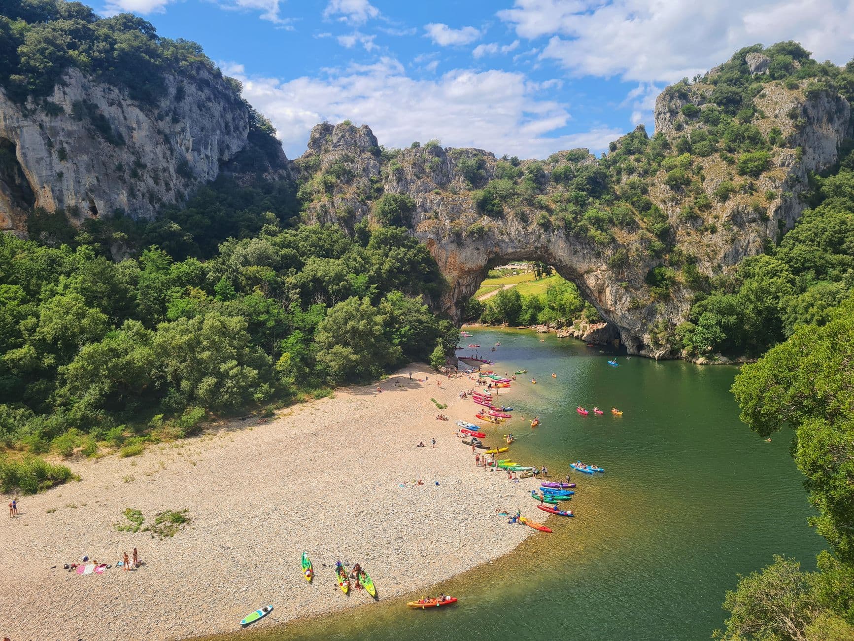 Vibrant scene of kayakers at the iconic Pont d'Arc in Ardèche Gorge, France.