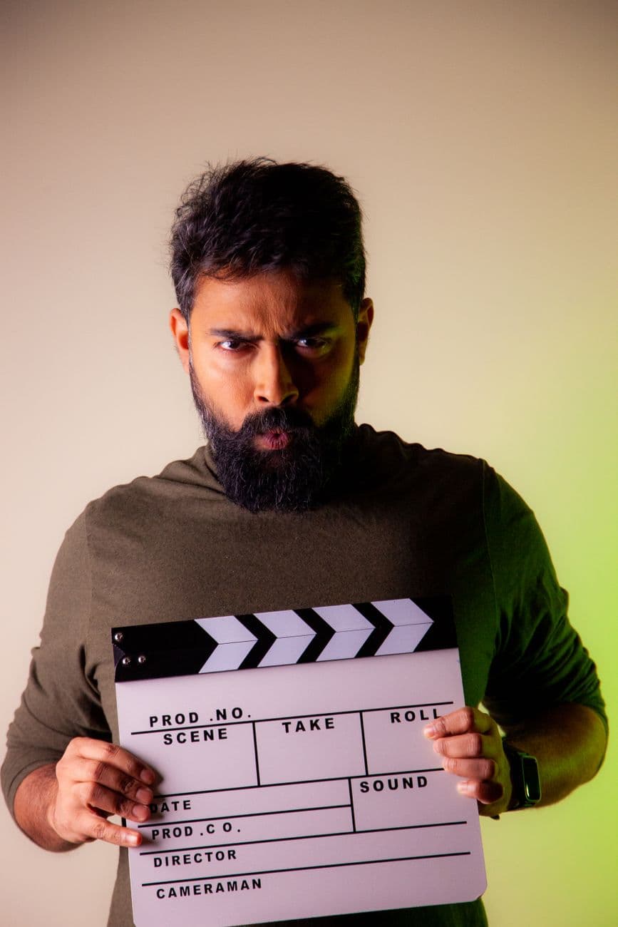 A serious bearded man holding a clapperboard, ready for a film studio shoot.