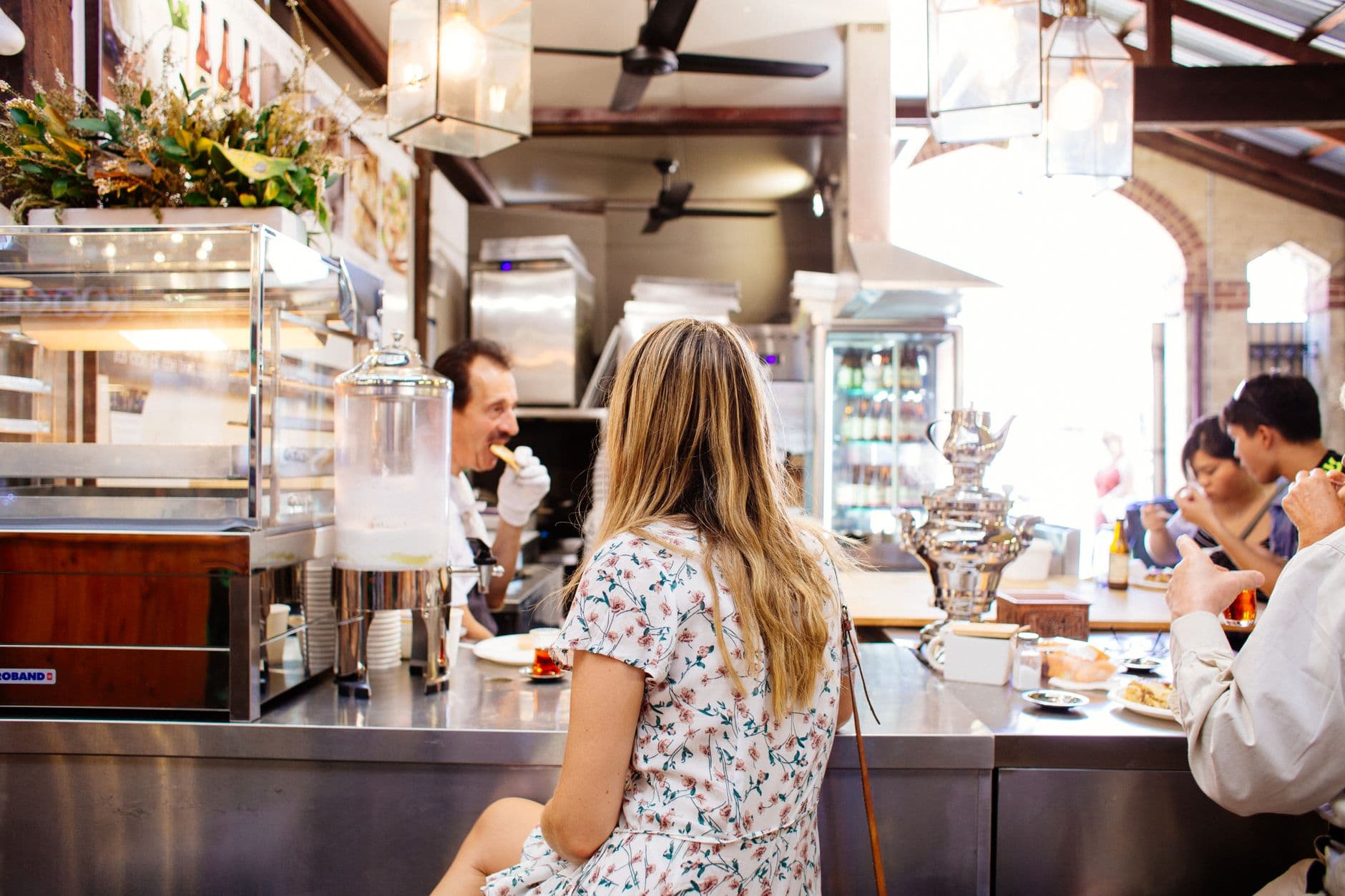 A woman with blonde hair sits at a cafe counter, enjoying a meal. Modern indoor setting.