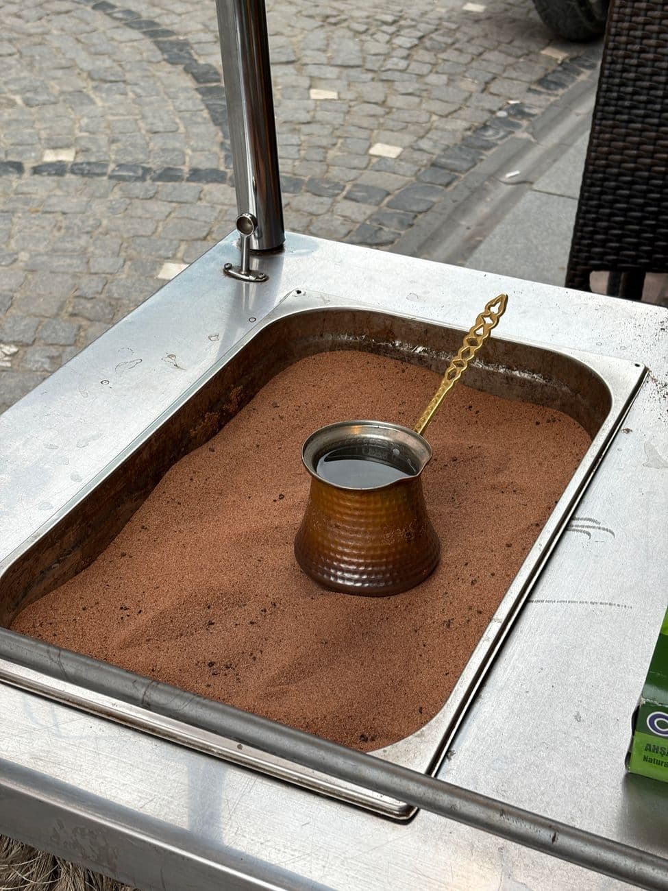 Traditional Turkish coffee brewing in a copper cezve on sand outdoors. Authentic Turkish style.