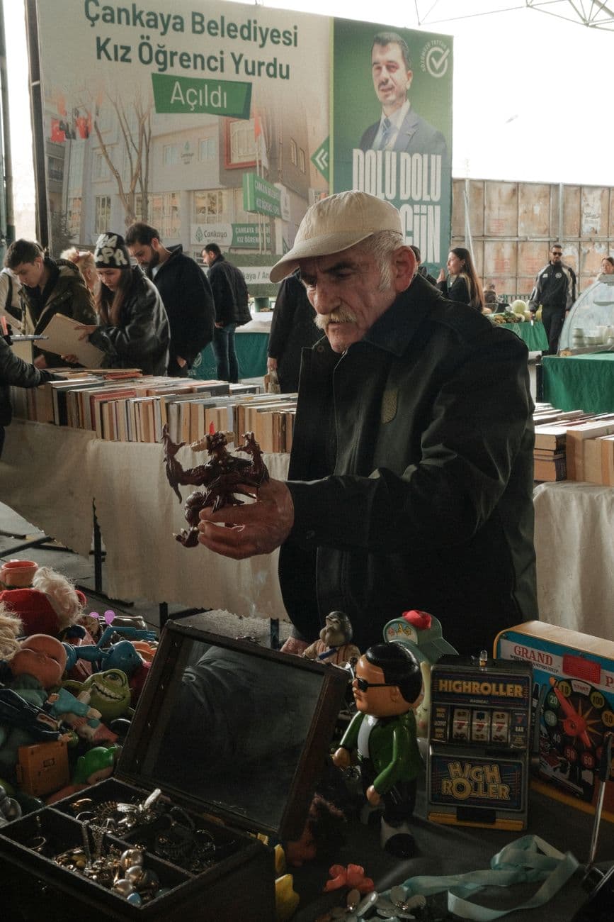 Elderly man explores toys at a flea market, surrounded by vintage items and bookstore setting.