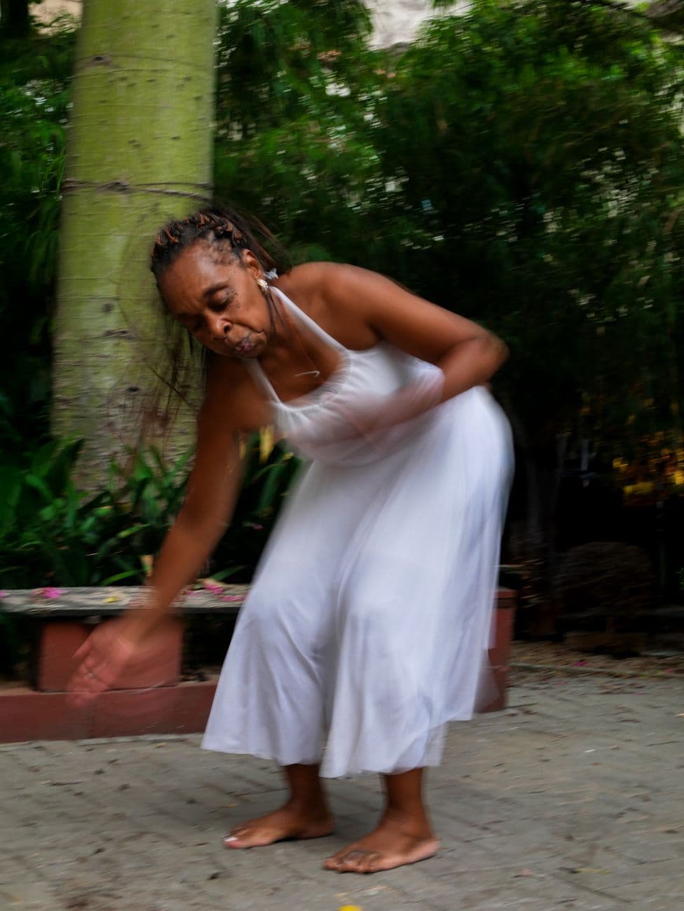Woman in a white dress gracefully dancing outdoors with blurred motion.