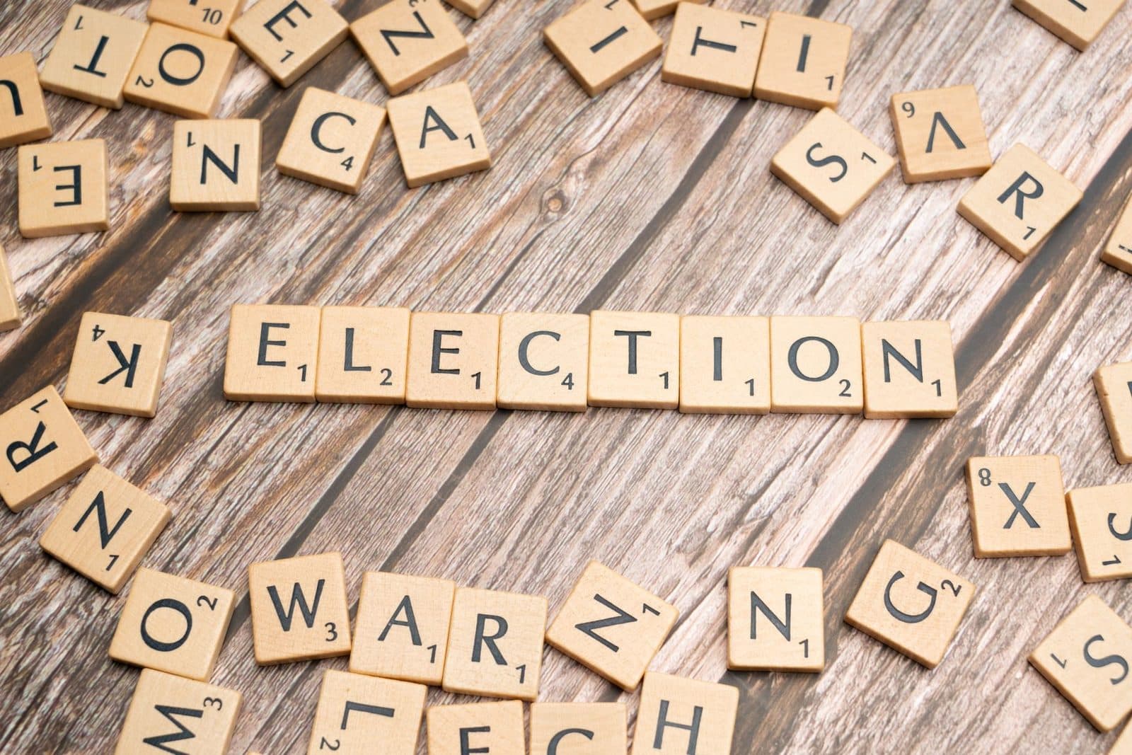 Wooden letter tiles form the word 'election' on a textured wooden surface, symbolizing voting.