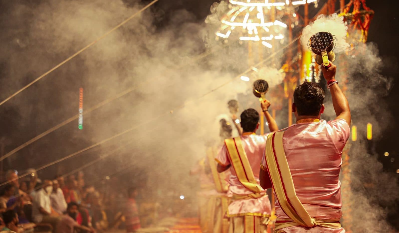 Men performing traditional rituals with incense in vibrant cultural festival setting.