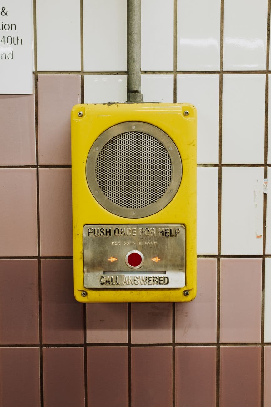 A yellow emergency call box mounted on a subway wall in Philadelphia, PA.