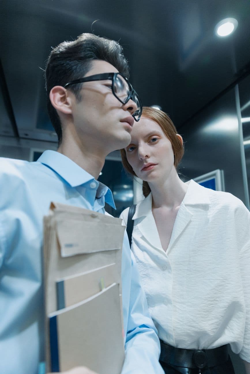 Two professionals in an elevator, conveying a serious mood indoors.