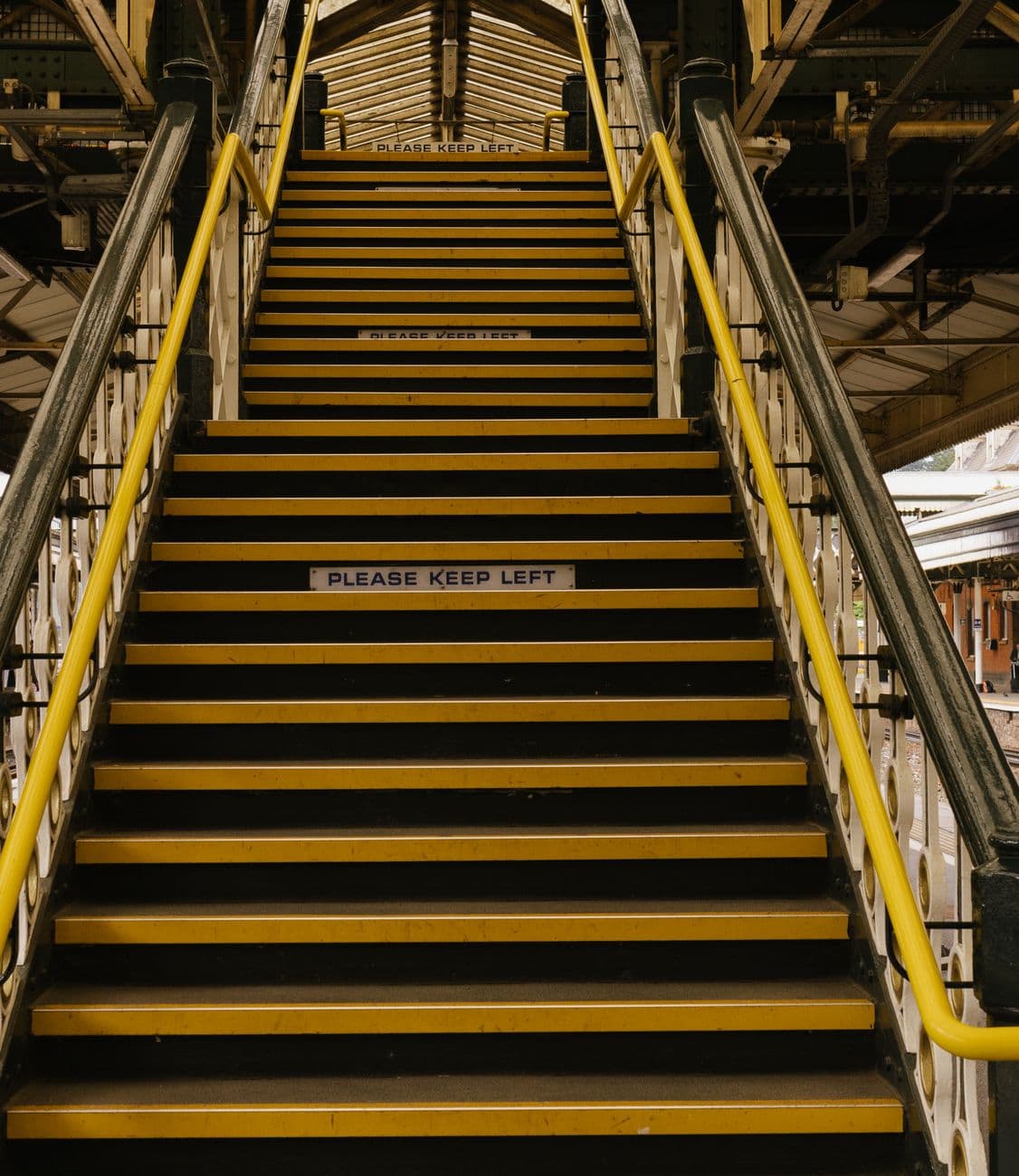 Vertical view of stairs with 'Please Keep Left' sign at a railway station.