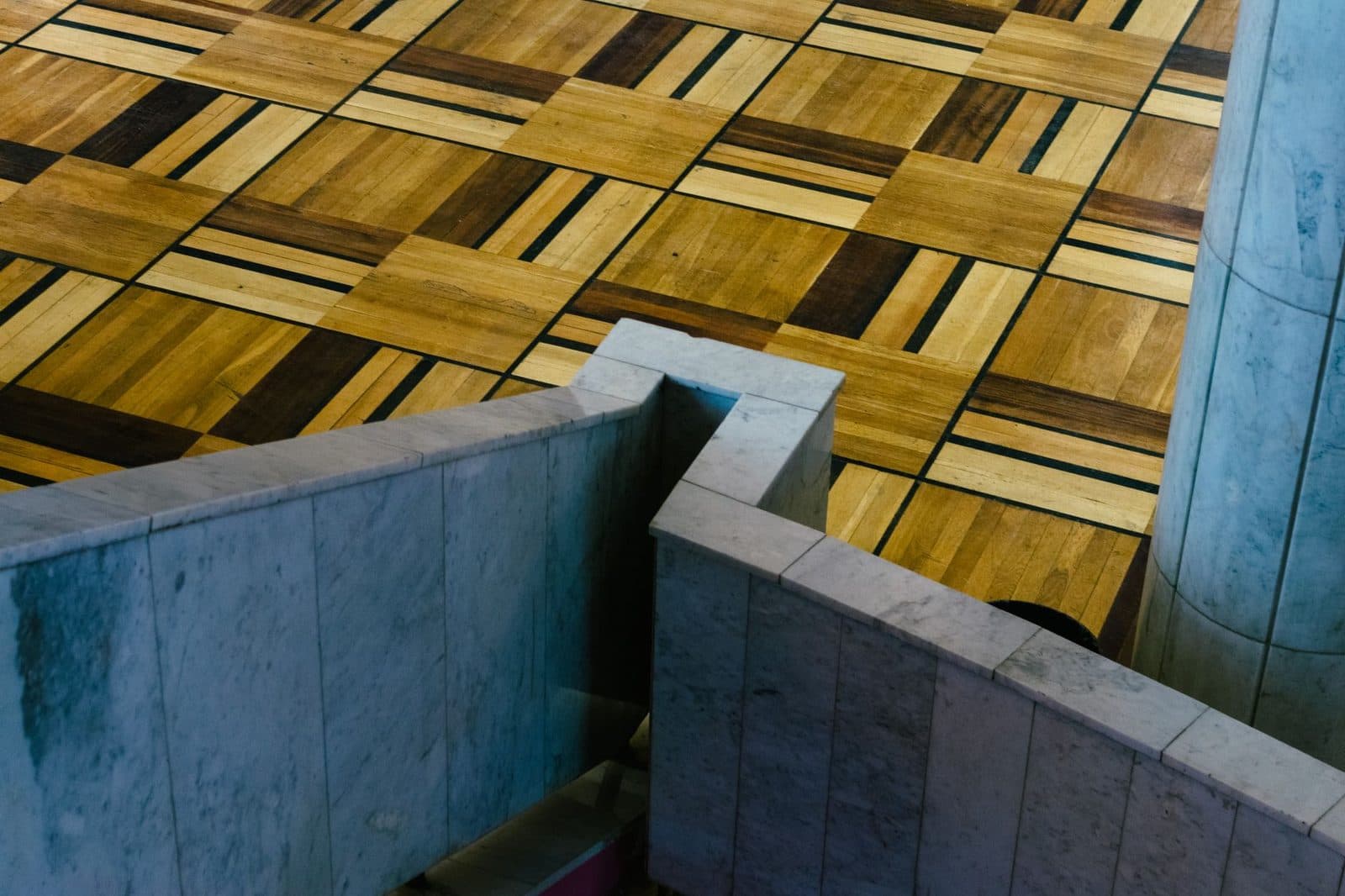 A top-down view of marble staircase leading to a decorative wooden floor with geometric patterns.