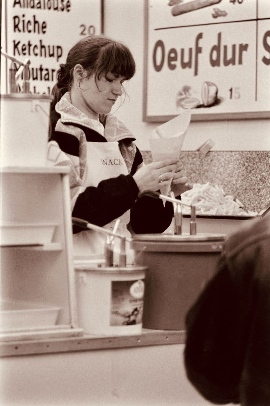 A woman preparing food at a street market stall in sepia tone, capturing the essence of street food culture.