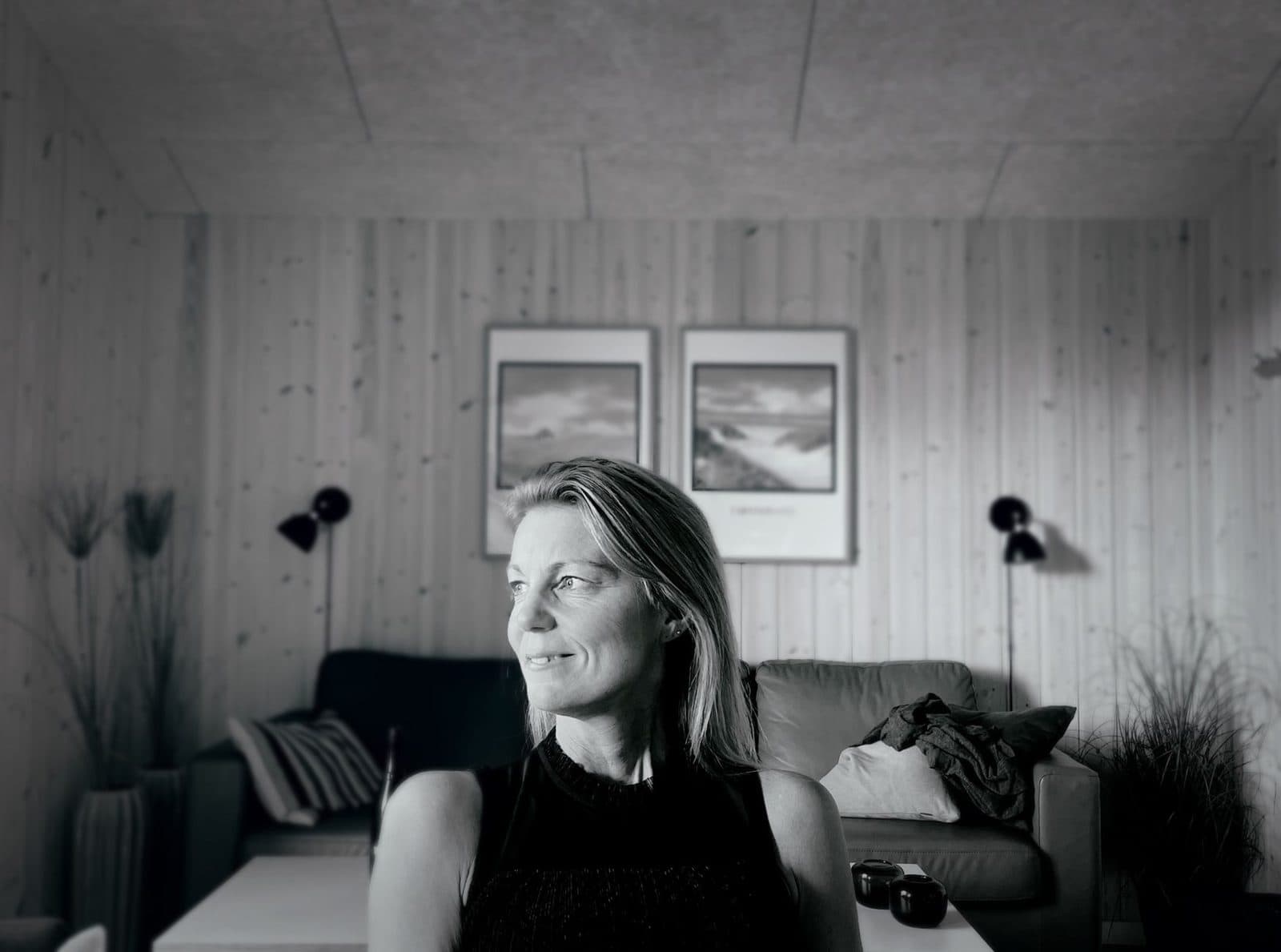 Black and white portrait of a woman in a cozy living room with contemporary decor.