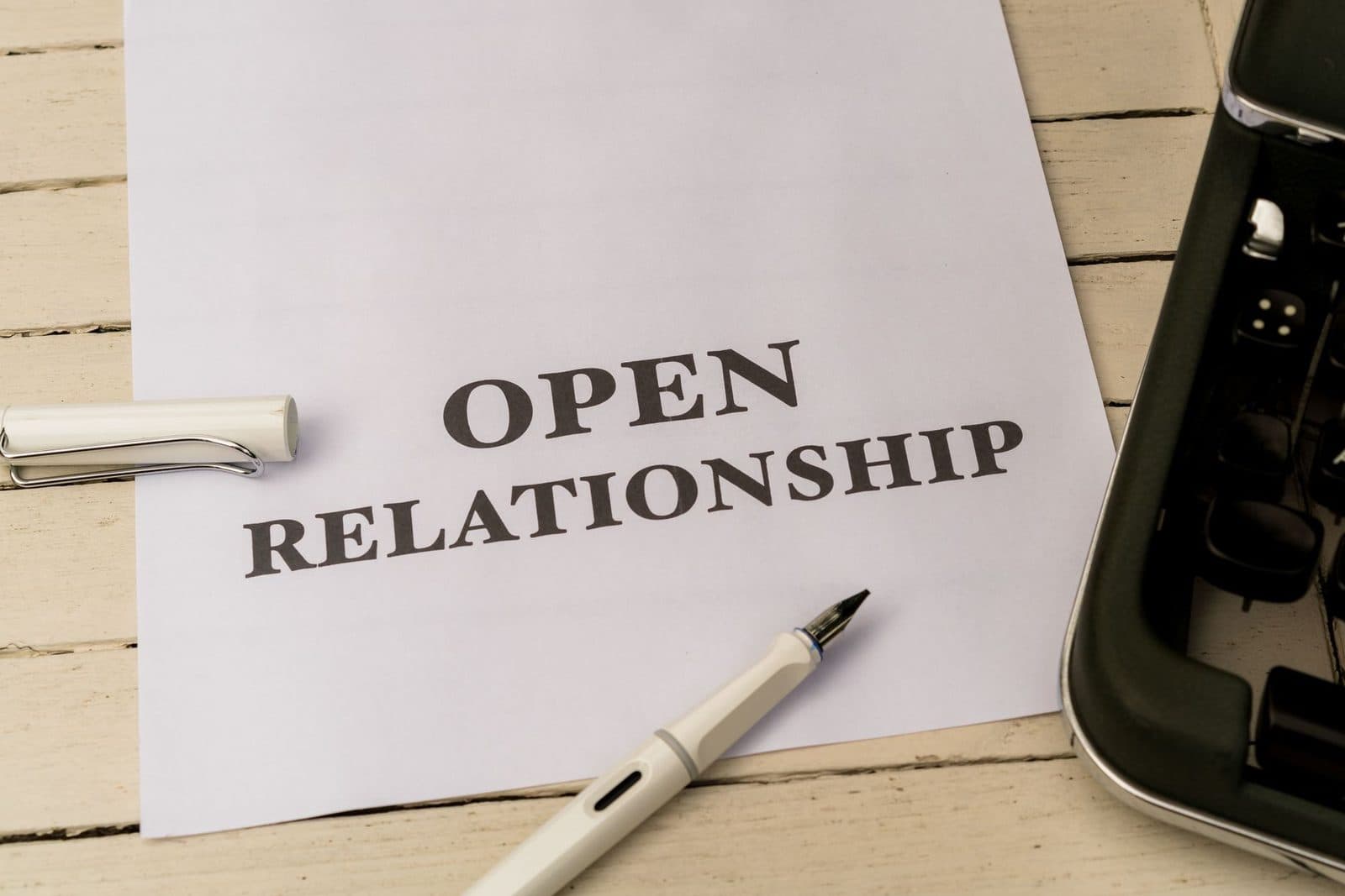 Image depicting the concept of 'Open Relationship' on paper with a pen and typewriter.