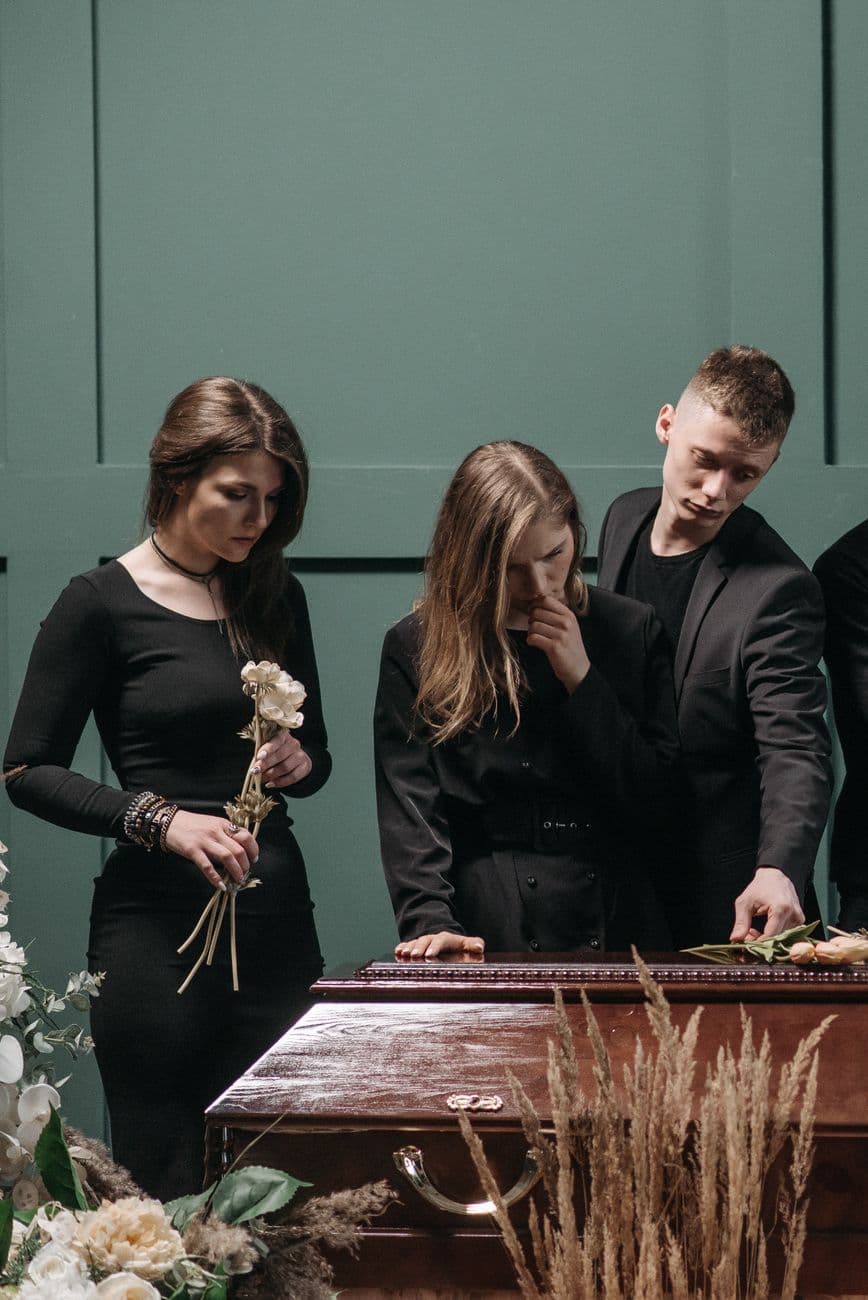 A somber gathering of people in black clothing at a funeral, conveying grief and solidarity.