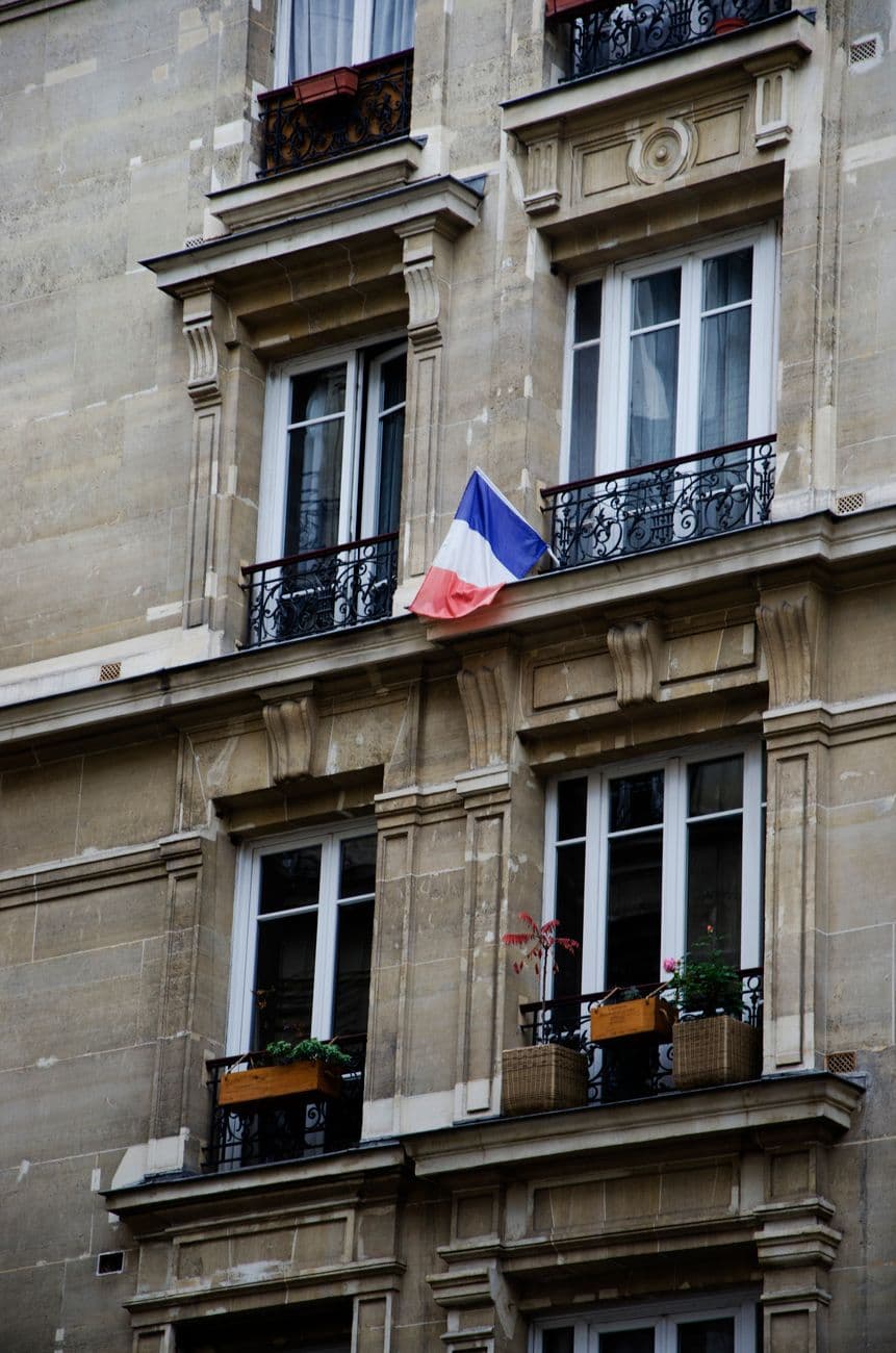 Elegant building facade featuring French flag and ornate balconies