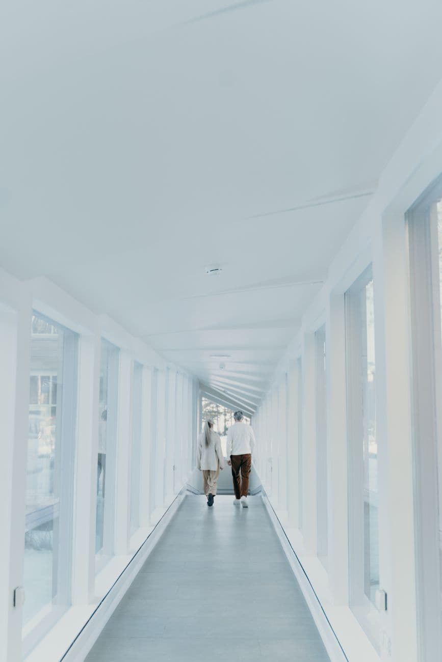 A senior couple walking together in a bright, modern indoor hallway.