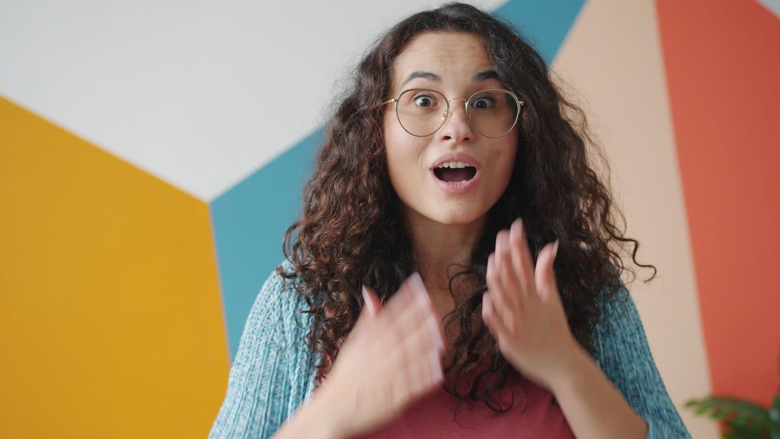 Surprised young woman expressing surprise with colorful geometric background indoors.