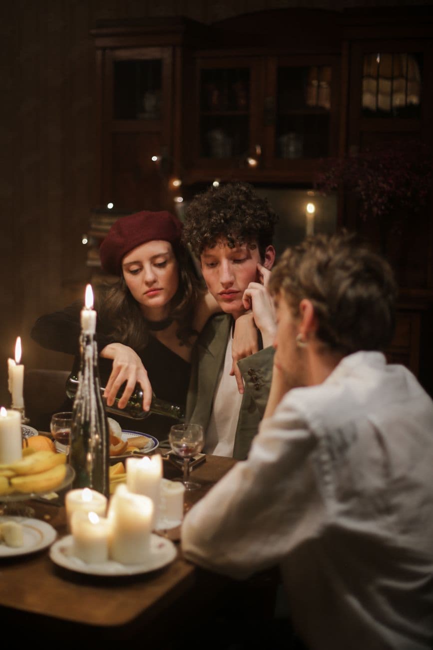 Intimate candlelit dinner scene with three friends enjoying an evening indoors.