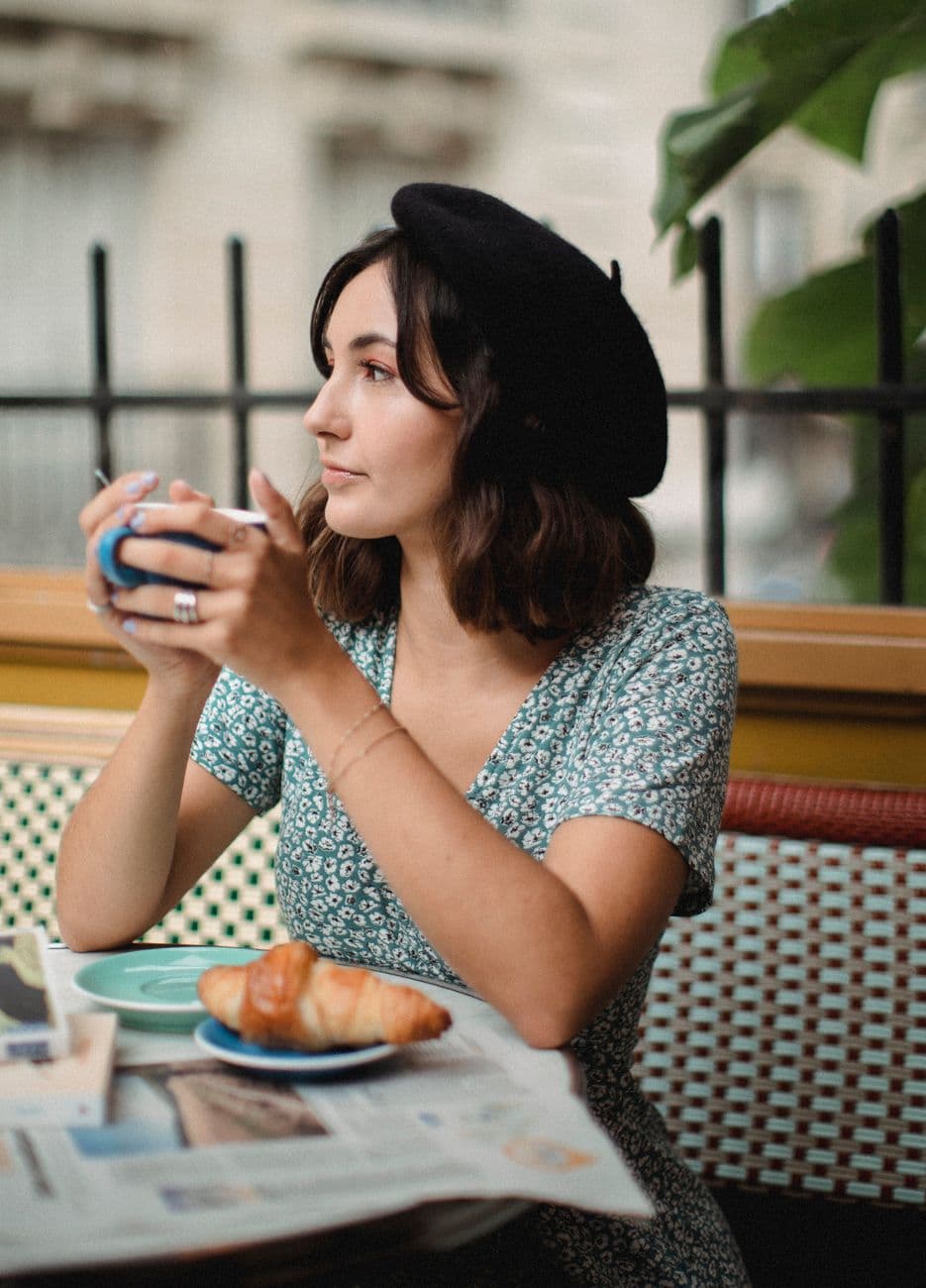 A woman in a beret with a coffee, enjoying a relaxed moment at a Parisian café.