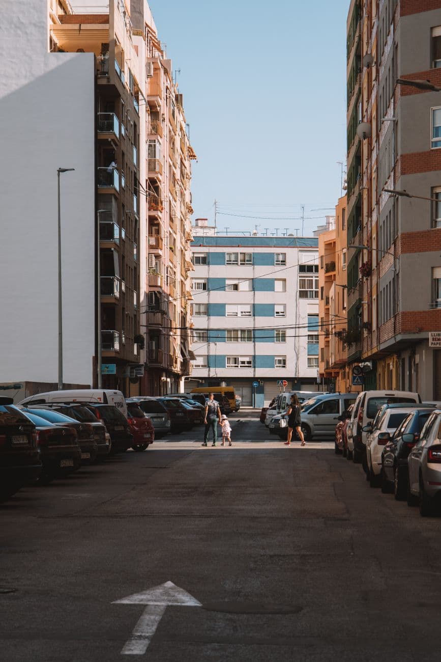 Street view of Valencia with parked cars and residential buildings, showcasing urban life.