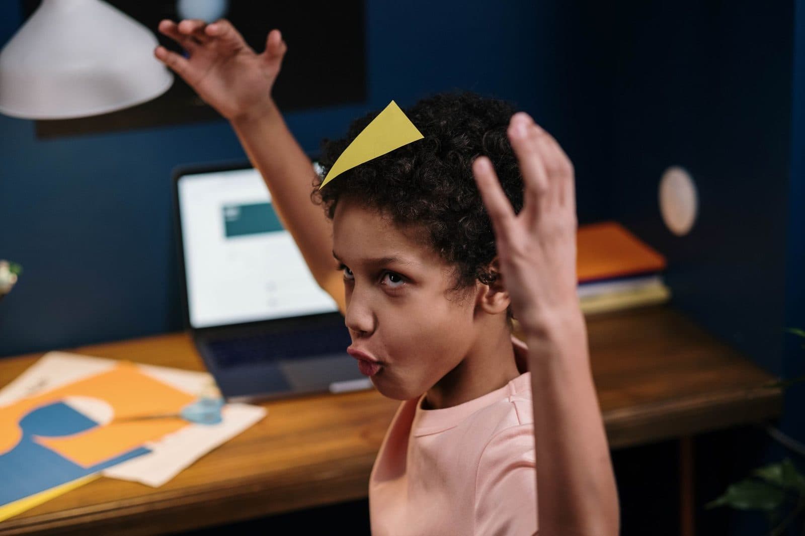 A playful child with afro hair enjoys a creative homeschooling session. Indoors setup.