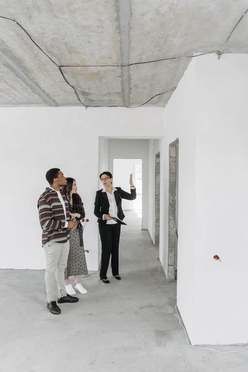 A real estate agent shows an empty property to potential buyers in a modern style.