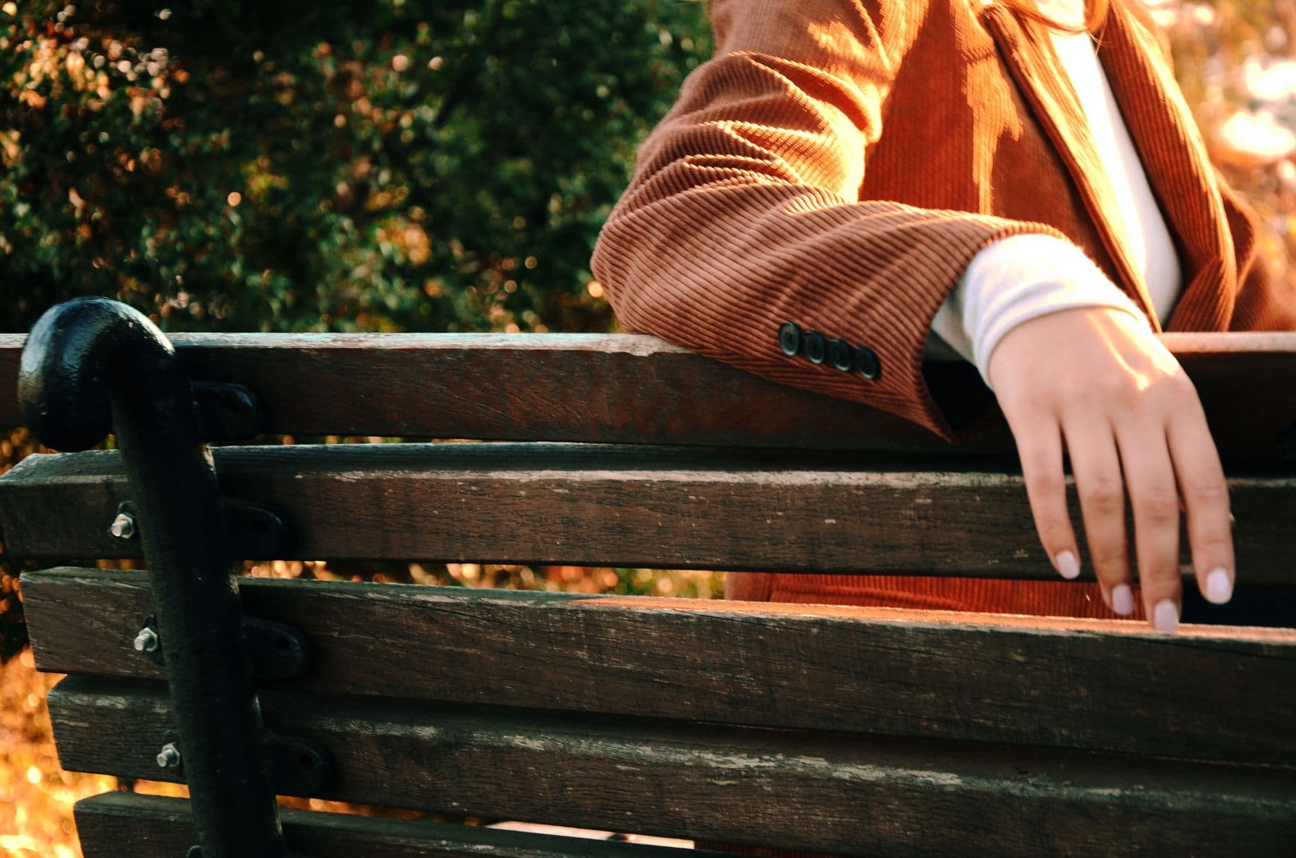 Close-up of a person in a brown suit resting on a wooden bench outdoors.