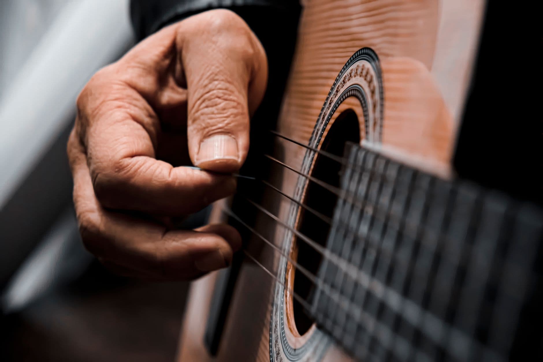 Detailed view of a hand strumming acoustic guitar strings, highlighting musical expression.