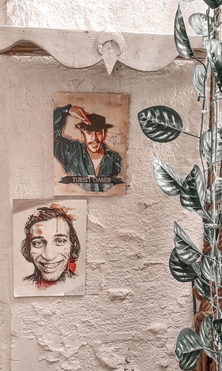 Creative wall art with two posters and decorative leaves on a plaster wall.