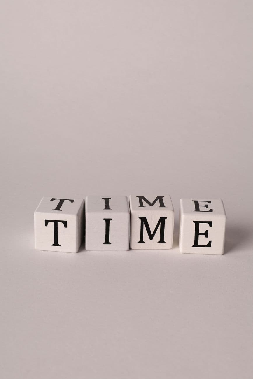 Close-up photo of 'TIME' spelled on dice with a neutral background.