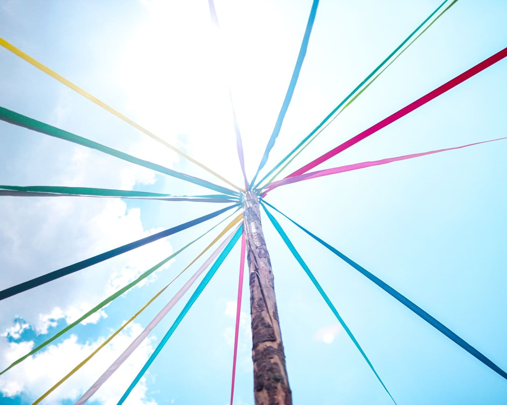 Colorful ribbons adorn a maypole on a sunny day, symbolizing spring festivities.