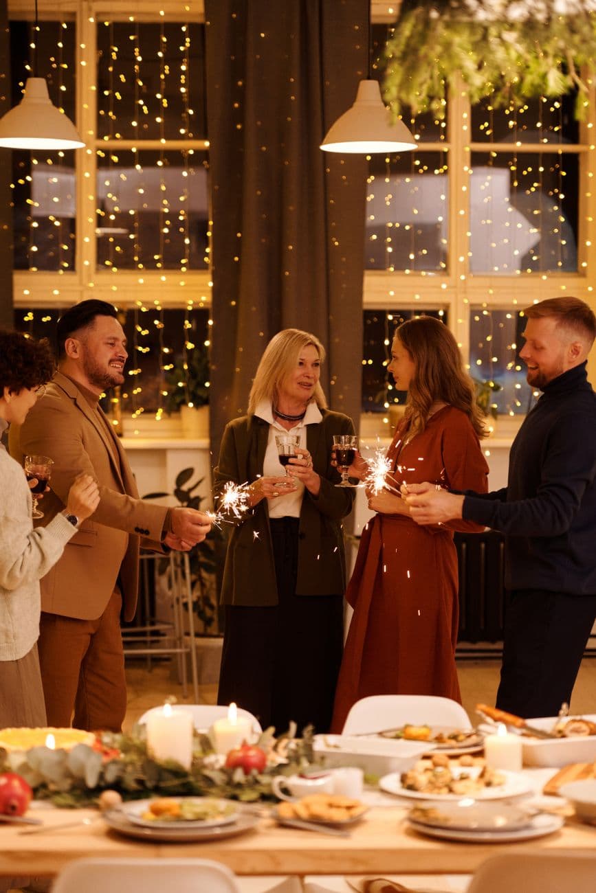 A joyful family gathering celebrating with sparklers and festive food indoors.