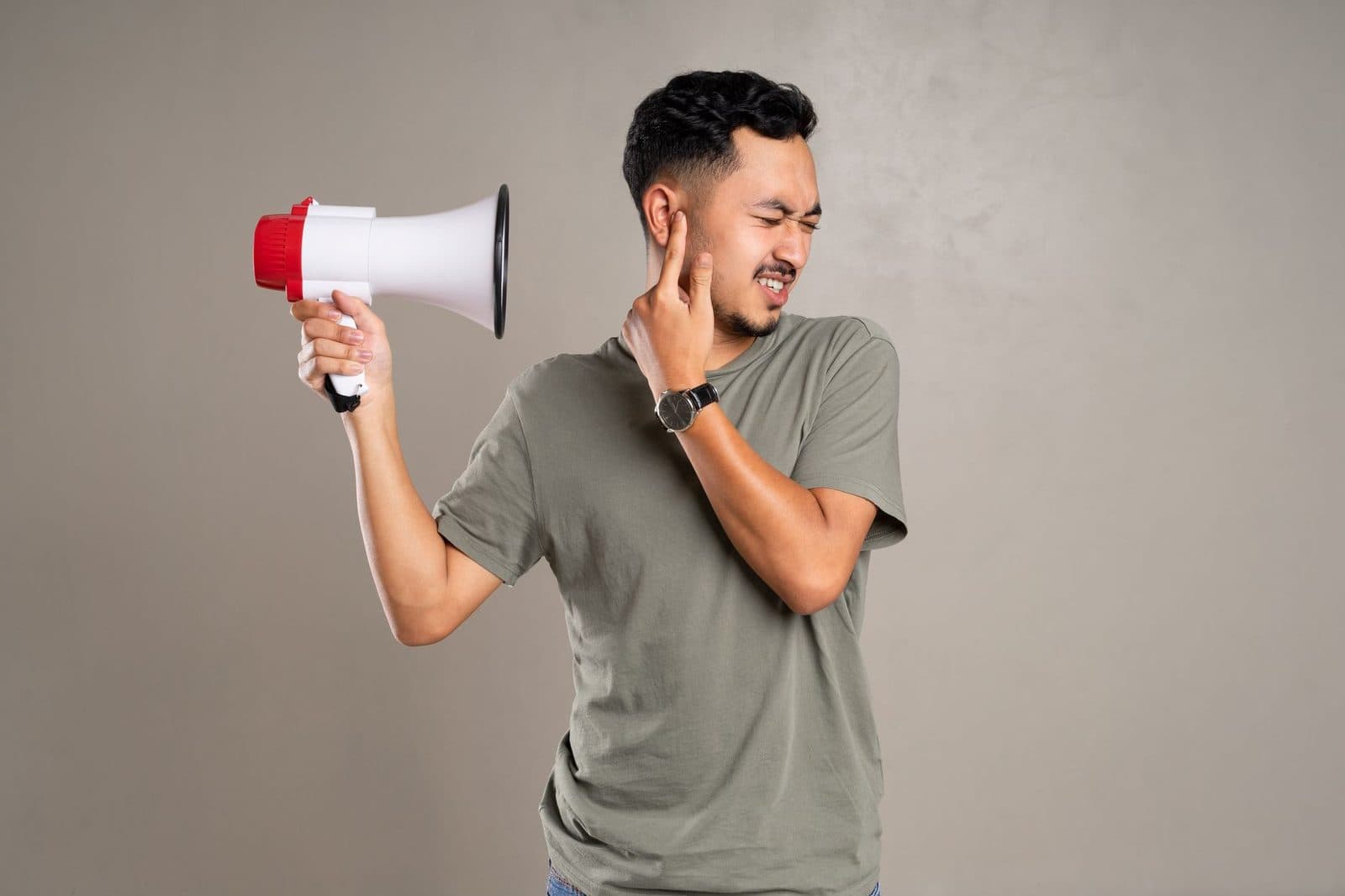 A man with a megaphone holding ear in discomfort, representing noise pollution or loud sounds.