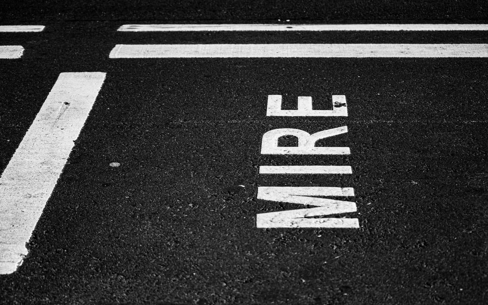 Black and white photo of "MIRE" street marking on Buenos Aires road.