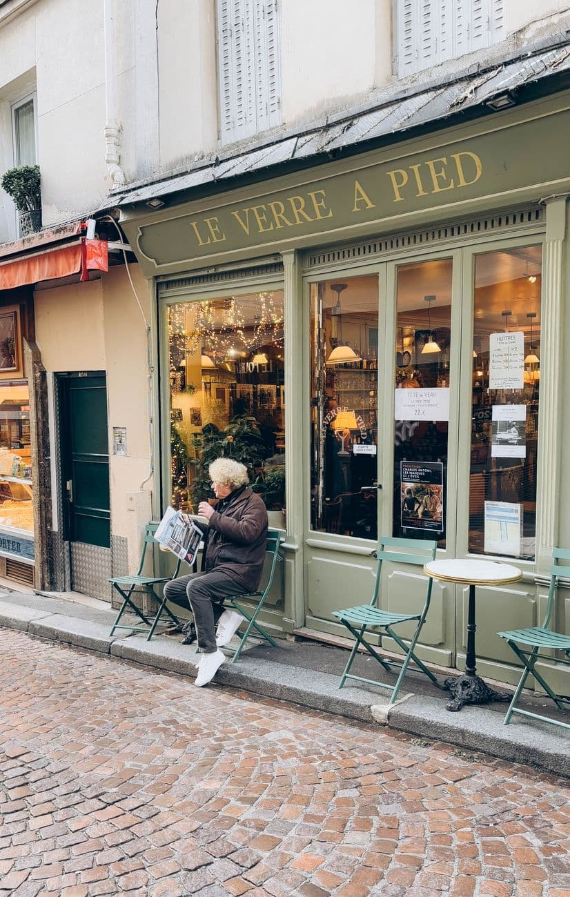 Charming Parisian café with an elderly man reading a newspaper outdoors.