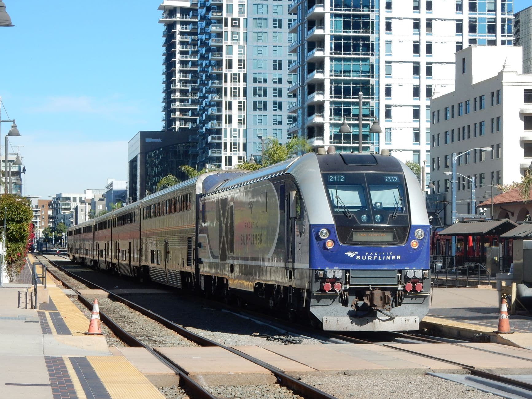 Pacific Surfliner train arriving at a downtown San Diego station, surrounded by modern urban architecture.