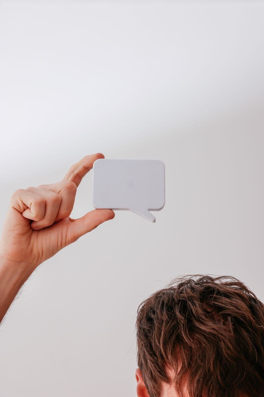 Close-up of a person holding a white speech bubble mockup against a white background.