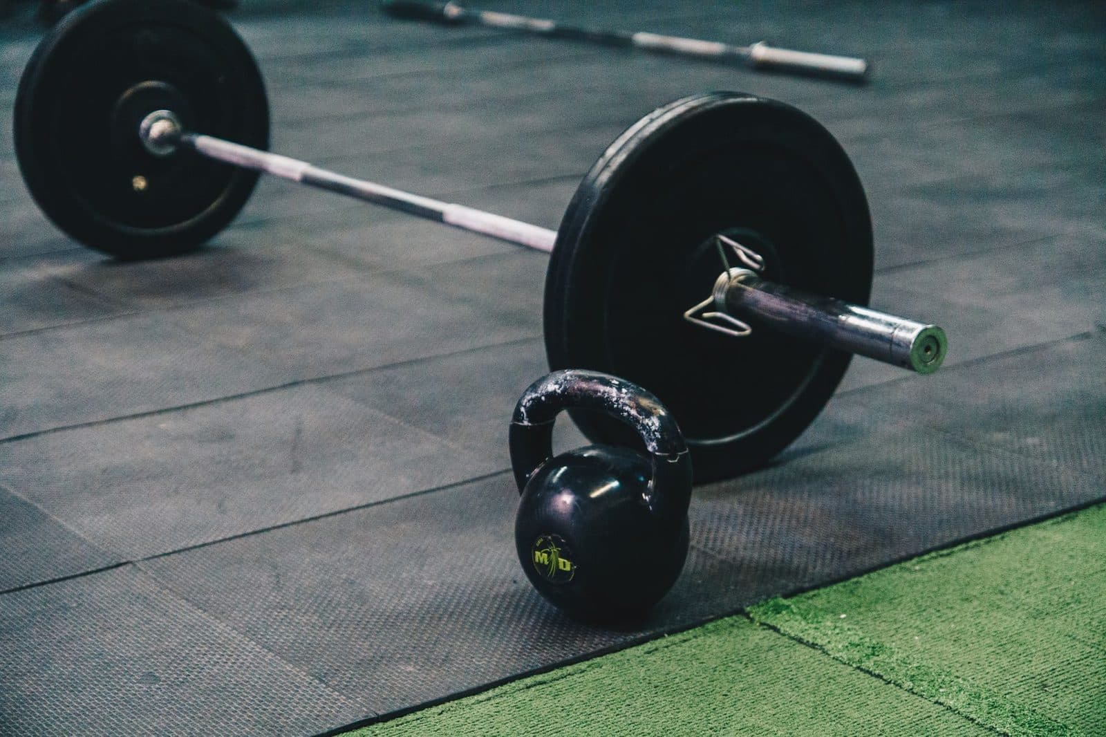 Barbell and kettlebell on gym floor, ideal for fitness and strength training themes.